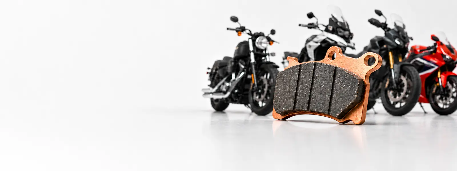 Pastilha de freio sinterizada em destaque diante de diferentes motocicletas